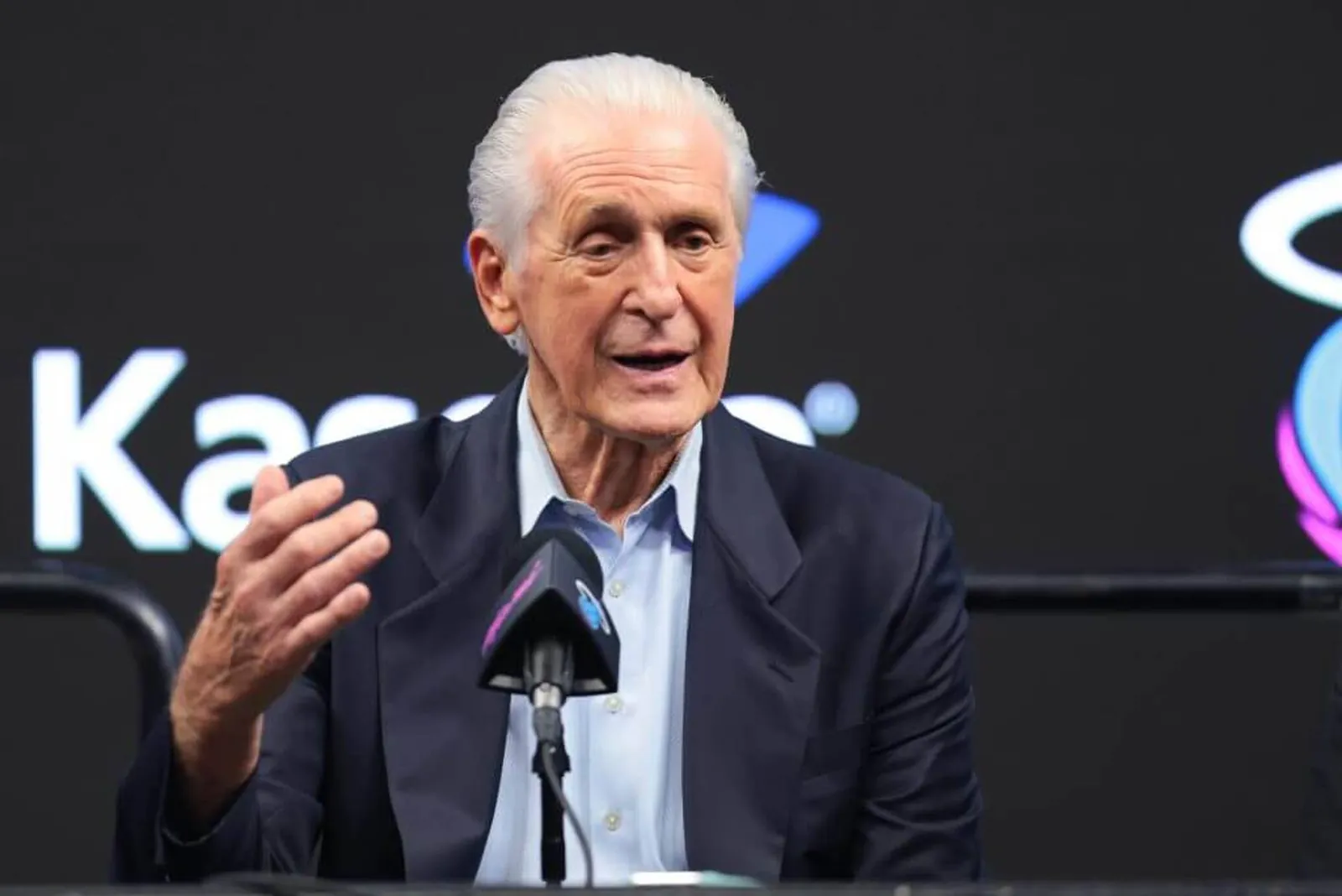 Miami Heat president Pat Riley speaks in front of a microphone while motioning with his right hand during a news conference.