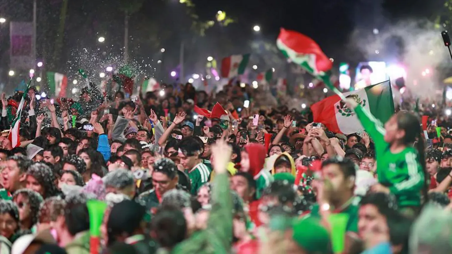 Getty Images A huge crowd of fans wearing Mexico's green football kit and waving the country's flag celebrate the team's 2-0 World Cup win against Ecuador in Mexico City at night.